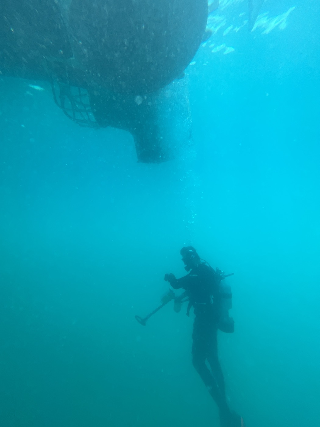 A diver descending with a metal detector beneath the salvage boat
