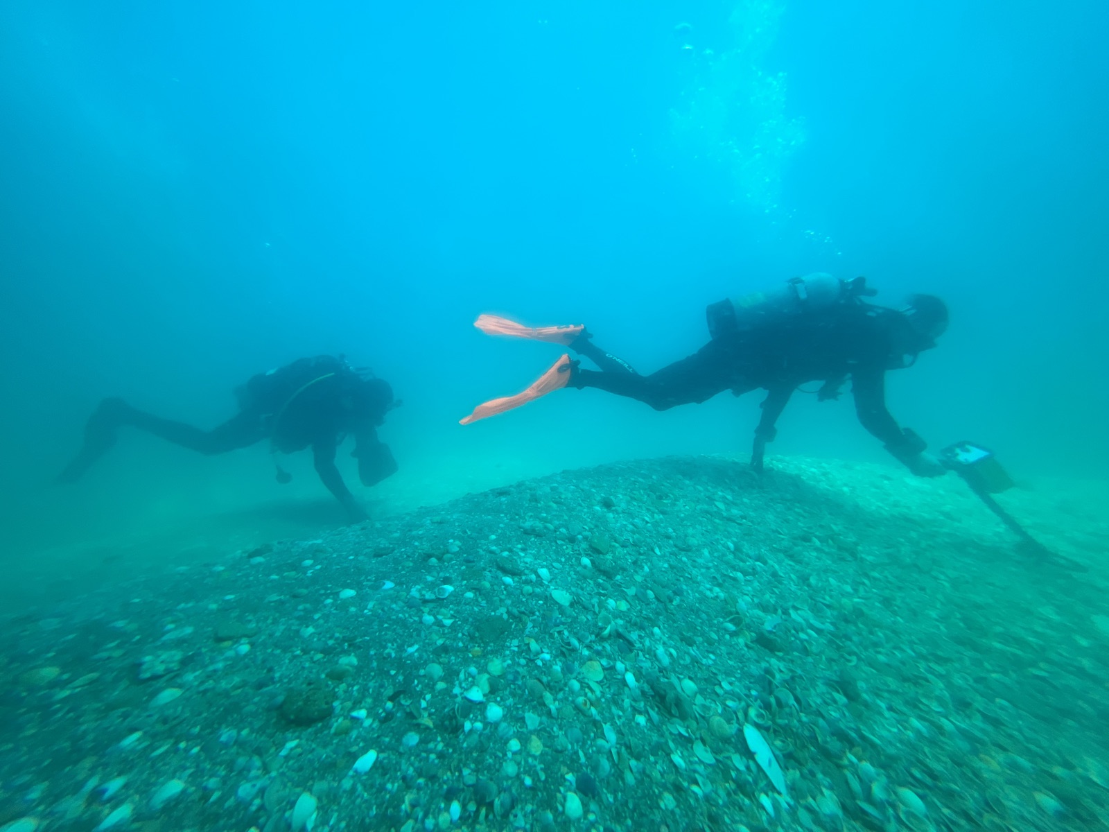 Two divers searching the seafloor with a metal detector